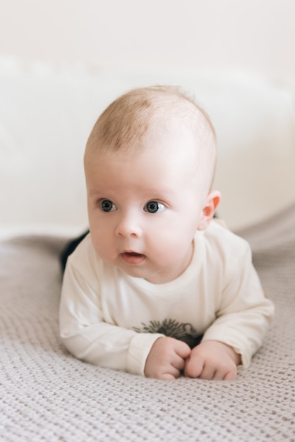 Handsome fashionable little boy lying on a blanket, with a sweet expression