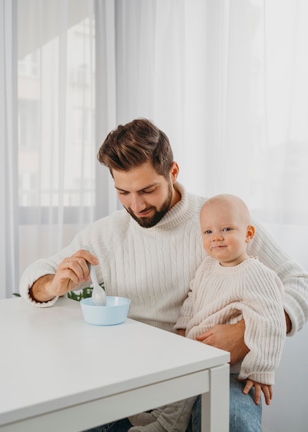 Photo handsome father feeding his babe