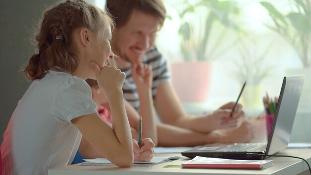 Photo handsome father helping his children with homework