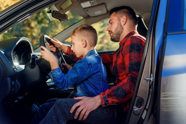 Handsome father pointing on something while teaching teen son driving car