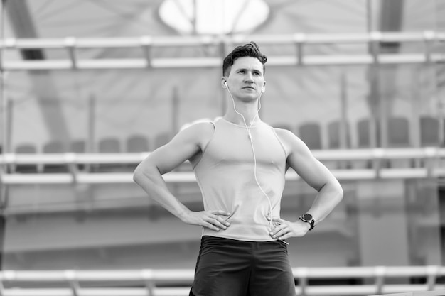 Handsome fit man listening motivational music for workout outdoors