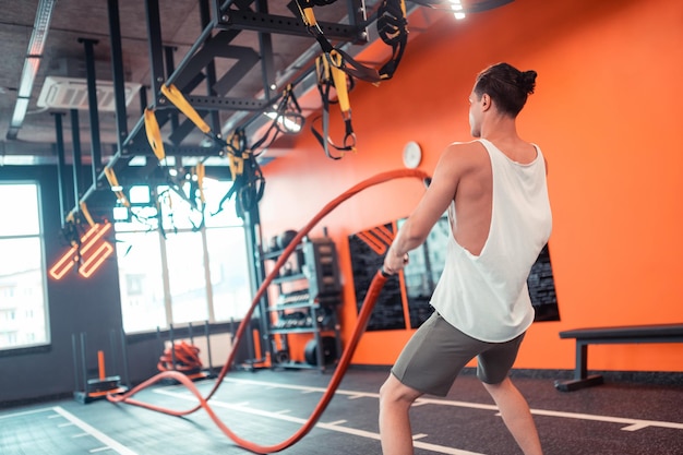 Handsome fit young man holding battling ropes