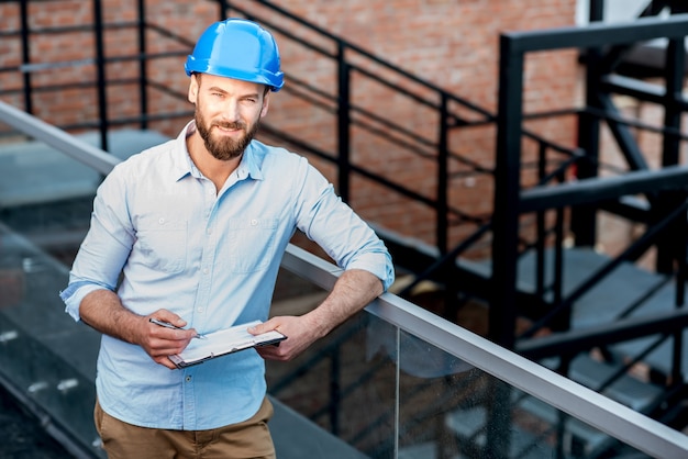 Handsome foreman or builder in helmet supervising a new structure