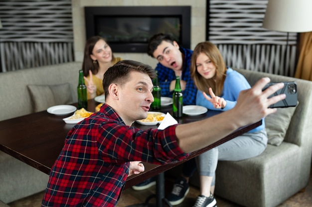 Amici belli che fanno selfie e sorridono mentre riposa al pub