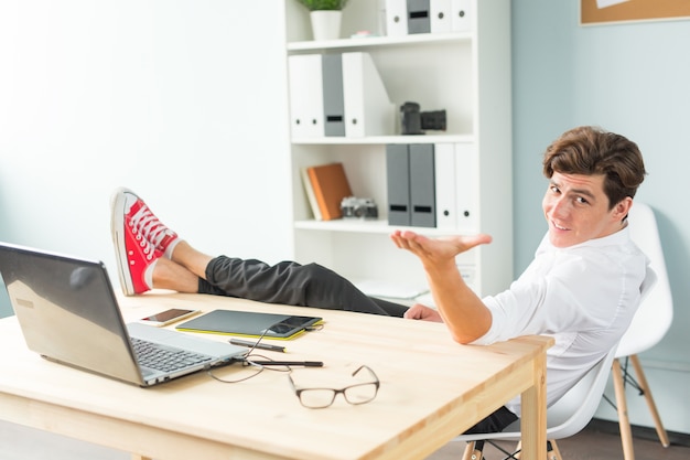 Handsome funny man in white shirt has a rest sitting at the office