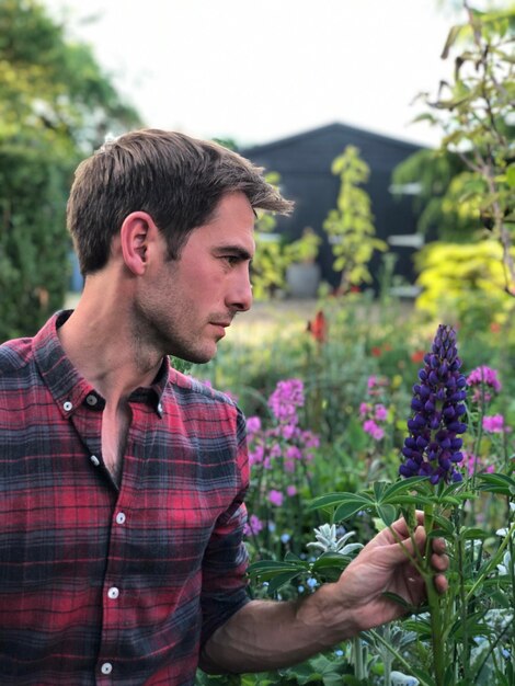 Foto un bel giardiniere che guarda il fiore di lupino.