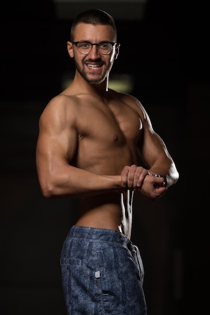 Фото Красивый выродок, стоящий в тренажерном зале и напрягающий мышцы, мускулистый спортивный культурист, фитнес-модель, позирующая после упражнений