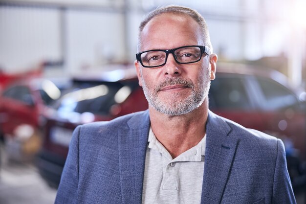 Handsome gentleman wearing glasses and gray jacket while looking at camera and smiling