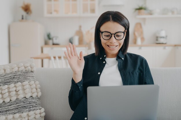 Handsome girl in glasses has video call and waving hand Communicating with colleagues for project