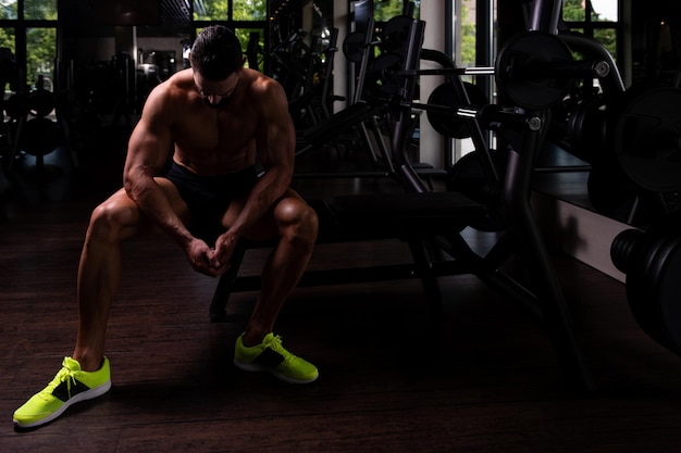 Handsome good looking and attractive young man with muscular\
body relaxing in gym