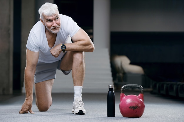 Foto bell'uomo anziano dai capelli grigi con peso kettlebell