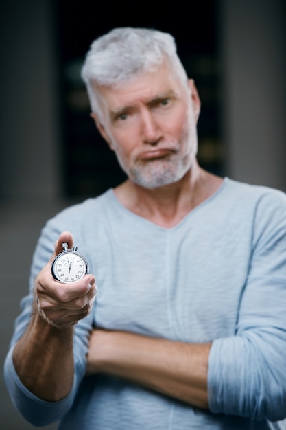 Handsome gray haired senior man with a stopwatch weight in his hand. Sport and health care concept