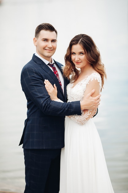 Handsome groom in black suit with beautiful bride in long white dress