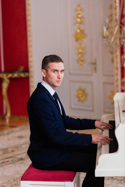 Handsome groom near the piano playing in a luxury interior