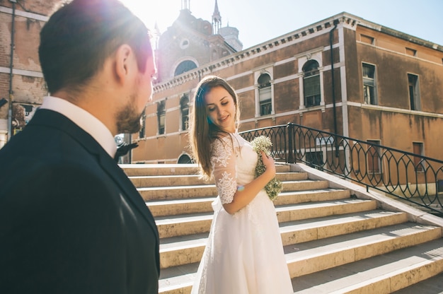 Handsome groom with happy bride in street