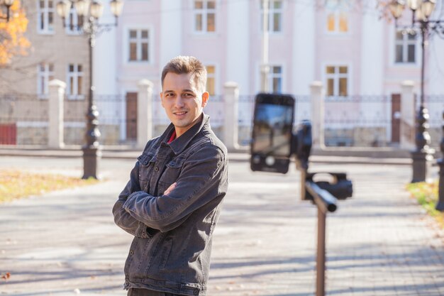 handsome guy blogger takes off a tripod in the street