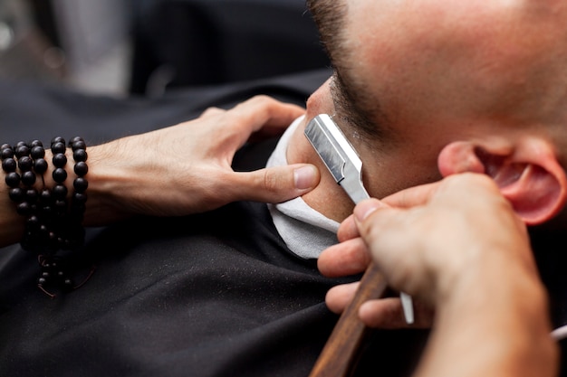 Handsome guy cut his beard with a razor blade