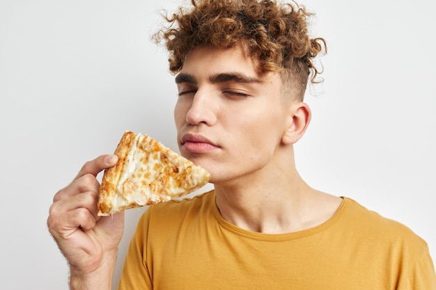 Handsome guy eating pizza posing closeup light background