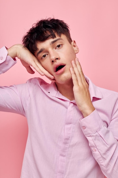 Handsome guy gestures with hands emotions hairstyle fashion pink background unaltered