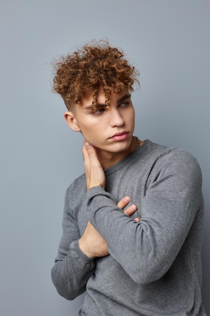 Handsome guy in a gray sweatshirt fashion studio Gray background