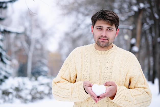 Handsome guy holding the heart out of the snow