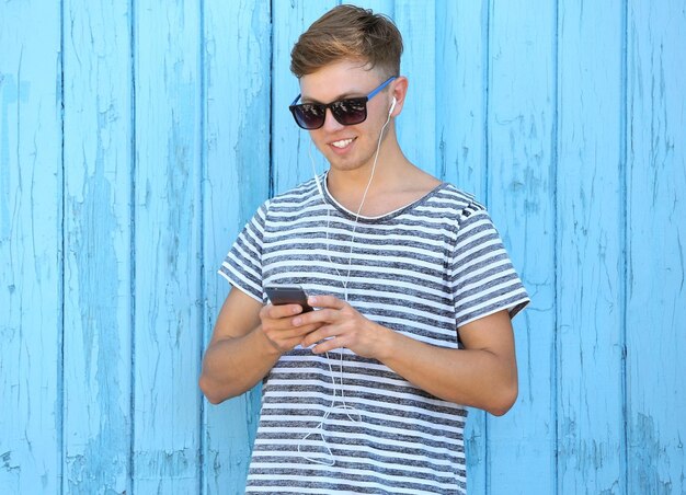 Handsome guy listening music on wooden background