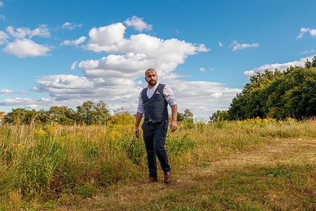 Handsome guy in a suit among the field against the blue sky