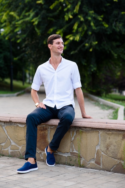 Handsome guy in a white shirt smiles and rests in the park.