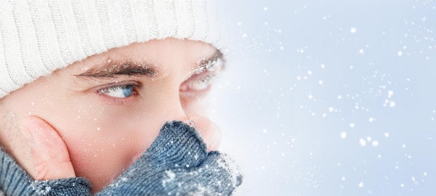 Handsome guy with blue eyes at the snow Winter portrait Copy space