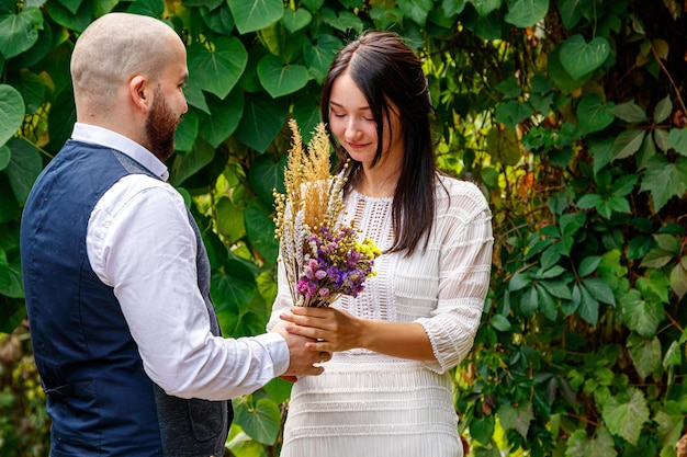 花を持つハンサムな男が婚約者にキスをする