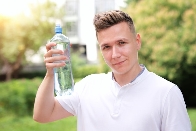 ハンサムな男若い幸せなのどが渇いた男のランナーはペットボトルから純粋な新鮮な水を飲んでいます