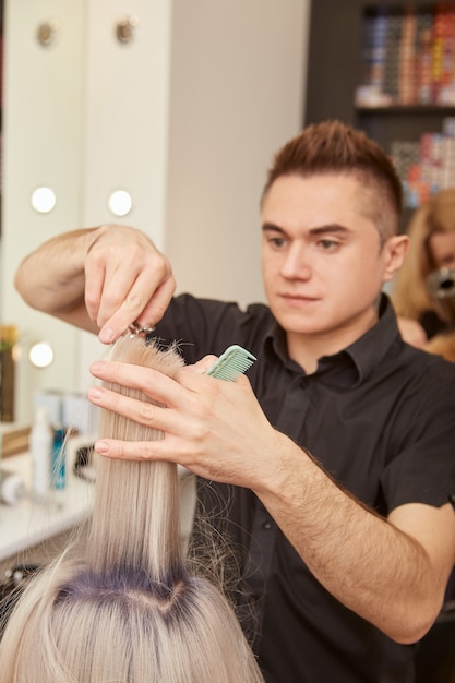 Handsome hairdresser cutting client hair in beauty salon