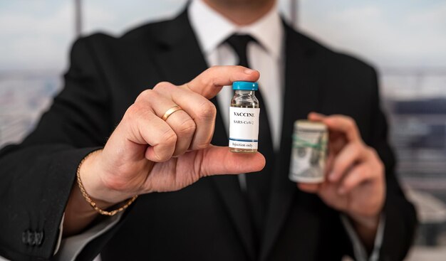 handsome handsome man in a chic suit from a cool brand holds a vaccine and dollars. Vaccination concept during a pandemic