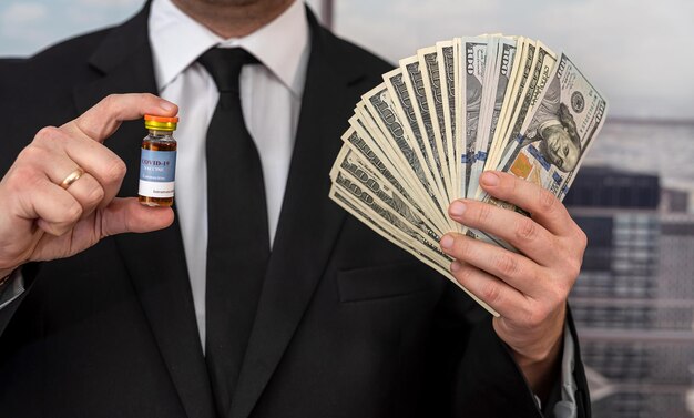 handsome handsome man in a chic suit from a cool brand holds a vaccine and dollars. Vaccination concept during a pandemic