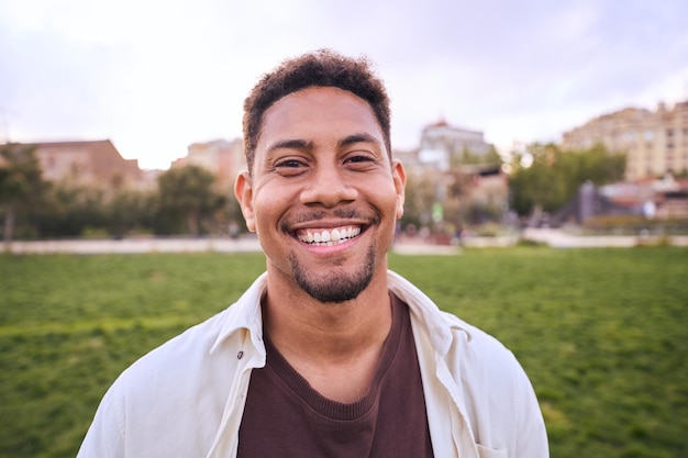 Handsome happy bearded man portrait of cheerful young man standing outdoors and smiling at camera