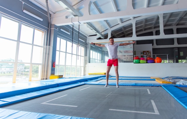 Handsome happy man jumping on a trampoline indoors.