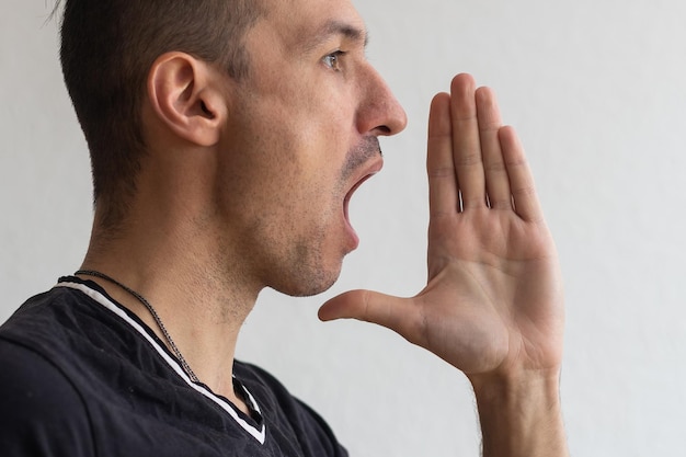 Handsome happy man wearing T-shirt, guy speaking loudly, isolated on white background