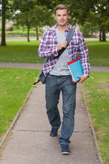 Handsome happy student carrying notebook and folder