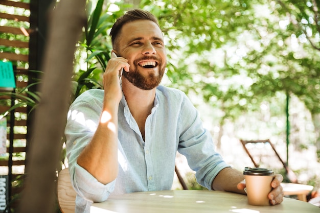 Photo handsome happy young bearded man talking by mobile phone.