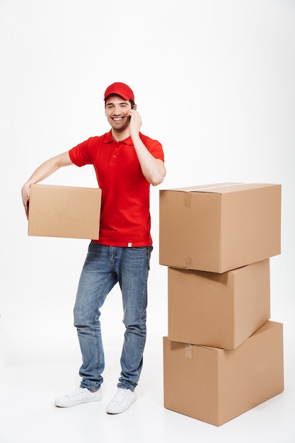 Handsome happy young delivery man talking by mobile phone.