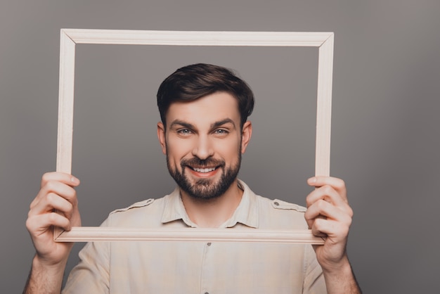 Handsome happy young guy holding wooden frame