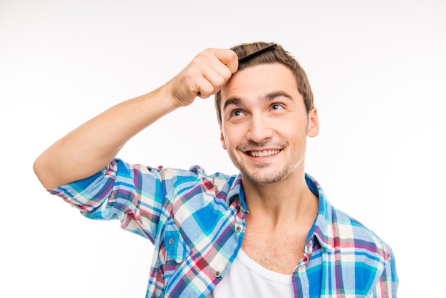 Handsome happy young man combing his hair