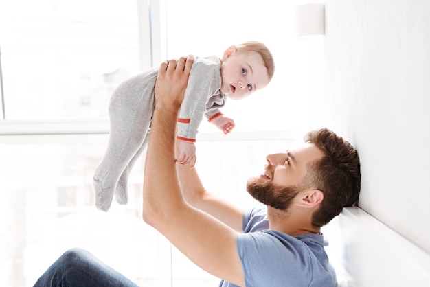 Handsome happy young man father dad having fun with his little baby