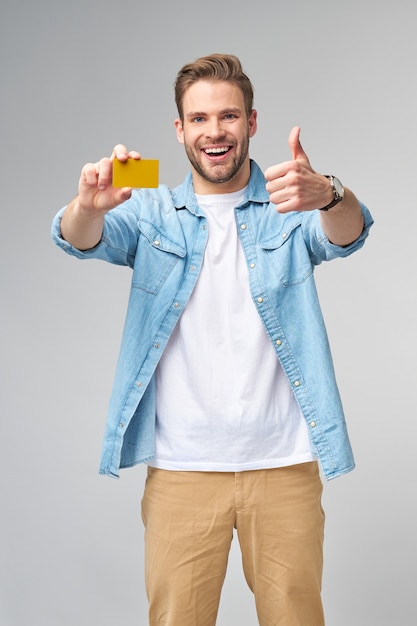 Фото Красивый счастливый молодой человек показывает пустую дисконтную карту банка cor