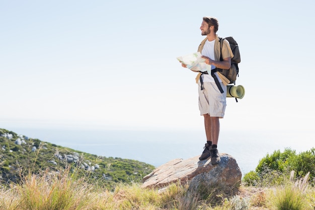 Красивый hiker, держащий карту на вершине горы