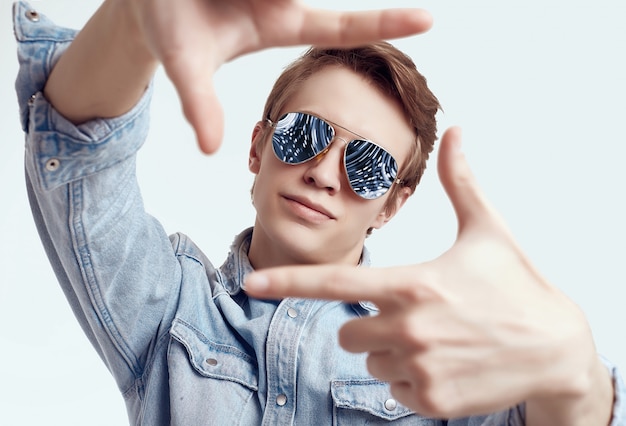 Handsome hipster man in fashion sunglasses wearing jeans jacket