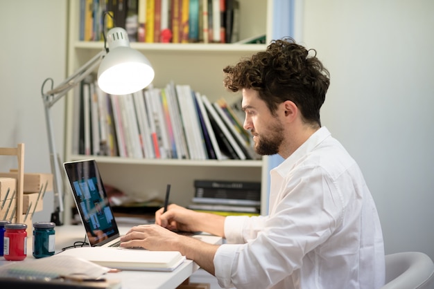 handsome hipster modern man working home using laptop