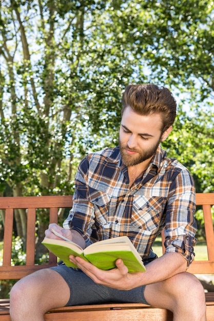 Handsome hipster reading in the park