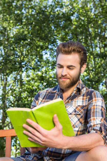 Handsome hipster reading in the park