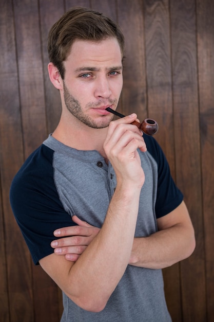 Handsome hipster smoking pipe